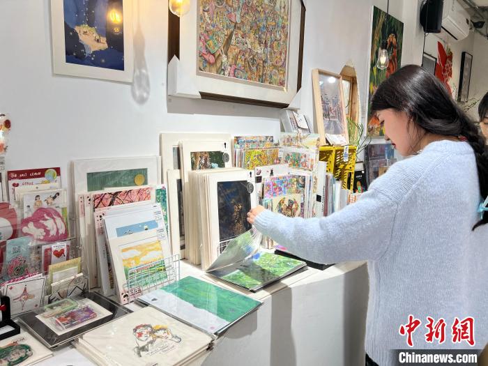 圖為藝術(shù)品商店內(nèi)，顧客挑選插畫作品?！＄婌?攝