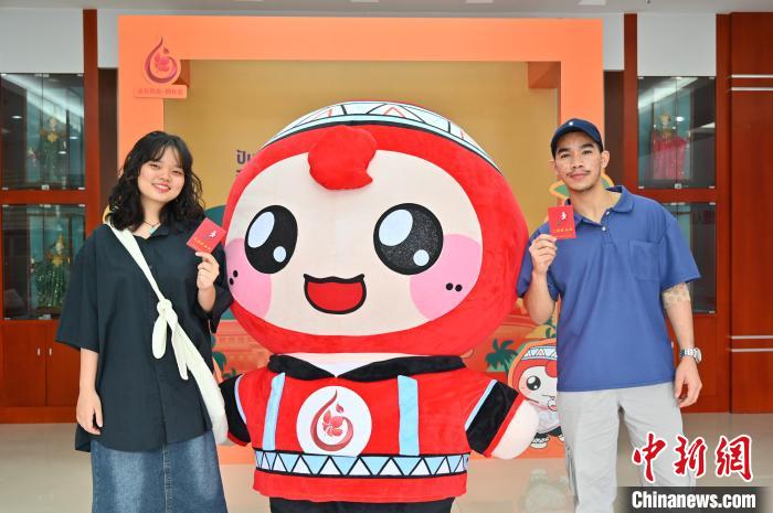 圖為泰國留學(xué)生手持獻血證與人偶合影?！∮峋?攝