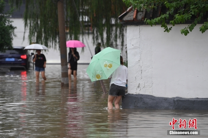 7月31日，市民行走在雨中的北京房山區(qū)瓦窯頭村。北京市氣象臺(tái)當(dāng)日10時(shí)發(fā)布分區(qū)域暴雨紅色預(yù)警信號(hào)。北京市水文總站發(fā)布洪水紅色預(yù)警，預(yù)計(jì)當(dāng)日12時(shí)至14時(shí)，房山區(qū)大石河流域?qū)⒊霈F(xiàn)紅色預(yù)警標(biāo)準(zhǔn)洪水。<a target='_blank' href='/'><p  align=