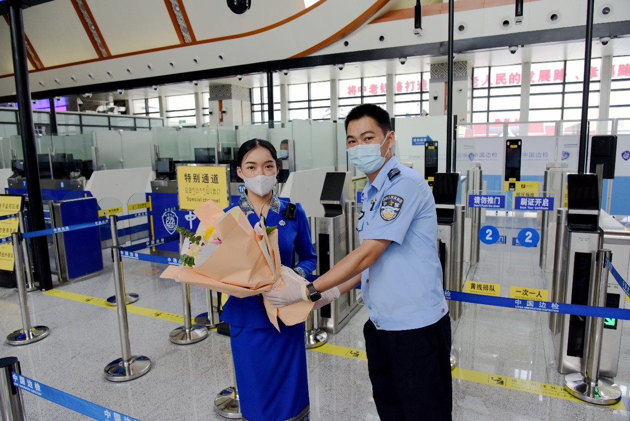 磨憨出入境邊防檢查站民警為中老鐵路第100萬(wàn)名出入境旅客，D888次國(guó)際旅客列車(chē)?yán)蠐爰藙?wù)員森達(dá)拉·妮緹婭（Sengdala Nitiya），送上鮮花。黃遠(yuǎn)飛 攝