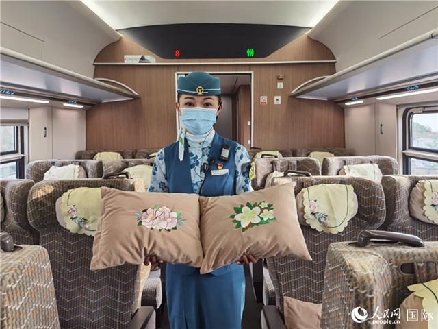 趙瑩靜展示中老鐵路國際旅客列車里帶有中國牡丹花和老撾占巴花刺繡圖案的靠墊。人民網(wǎng)記者 杜明明攝