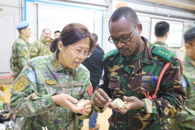 圖為維和官兵與外軍人員共同包餃子。胡光明攝