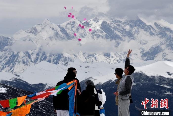 圖為5月14日，游客在西藏林芝色季拉山觀景臺拋灑“隆達”(風(fēng)馬旗，藏族民眾的一種祈福方式)?！±盍?攝