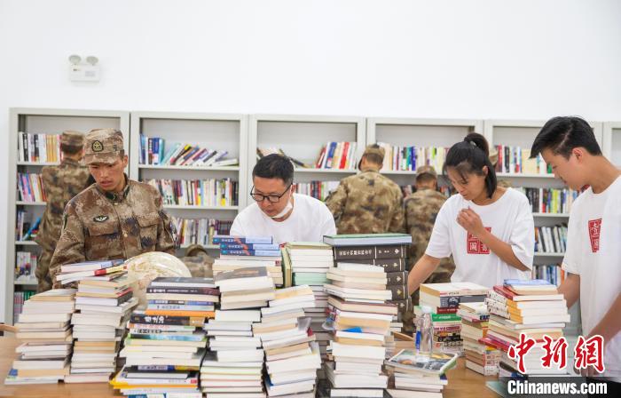 圖為志愿者們和邊防戰(zhàn)士整理圖書。　劉曉東 攝