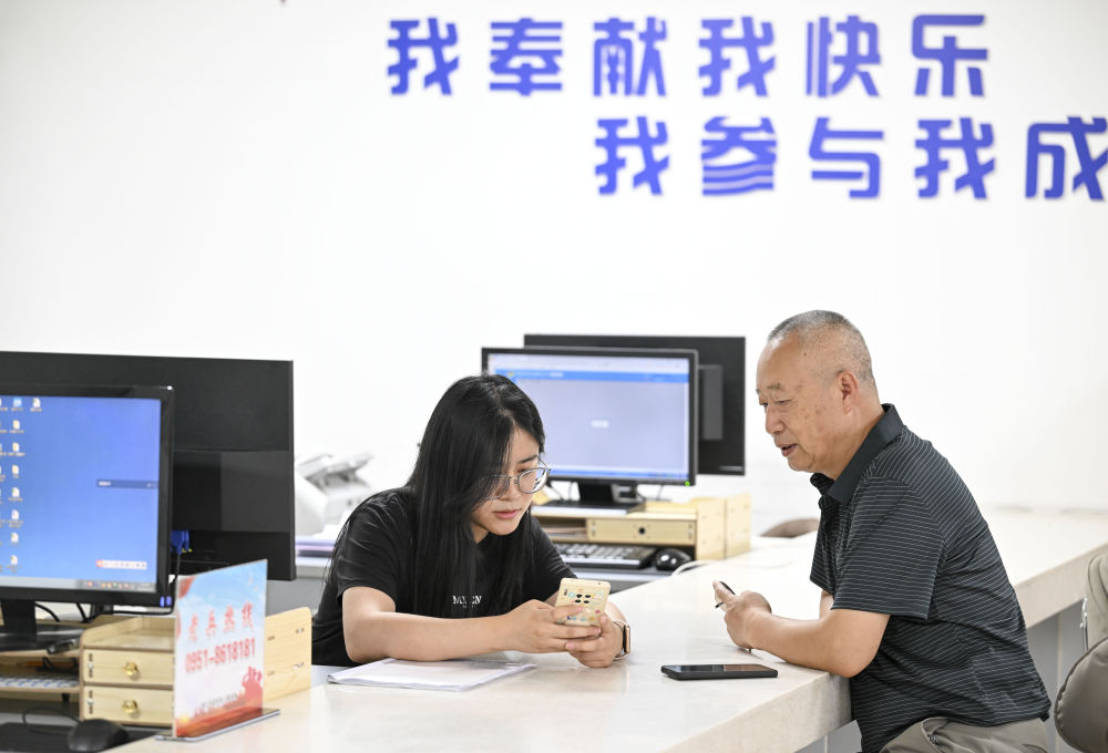 2024年6月20日，在寧夏銀川市金鳳區(qū)長城花園社區(qū)黨群服務中心，工作人員幫助居民辦理業(yè)務。圖片來源 新華社
