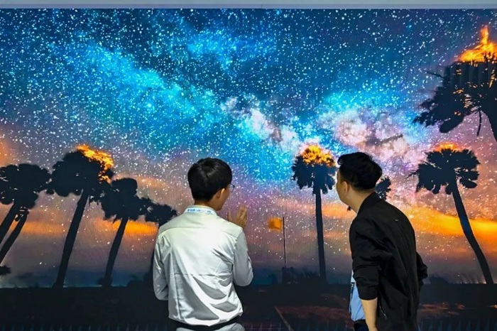 長春光博會希達(dá)電子展區(qū)，一位工作人員正在給一位觀眾講解。（長春新區(qū)供圖）