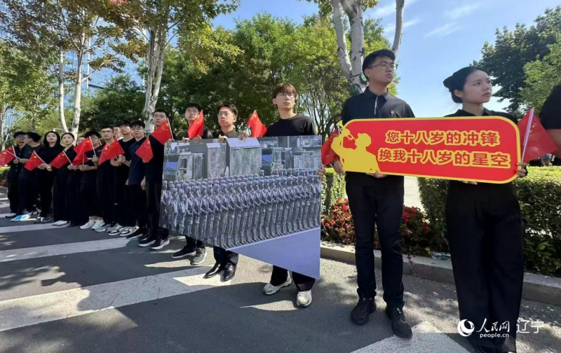沈陽市人民廣場上，大學(xué)生們手持閱兵的圖片，告慰英烈。人民網(wǎng)記者 周頌雪攝