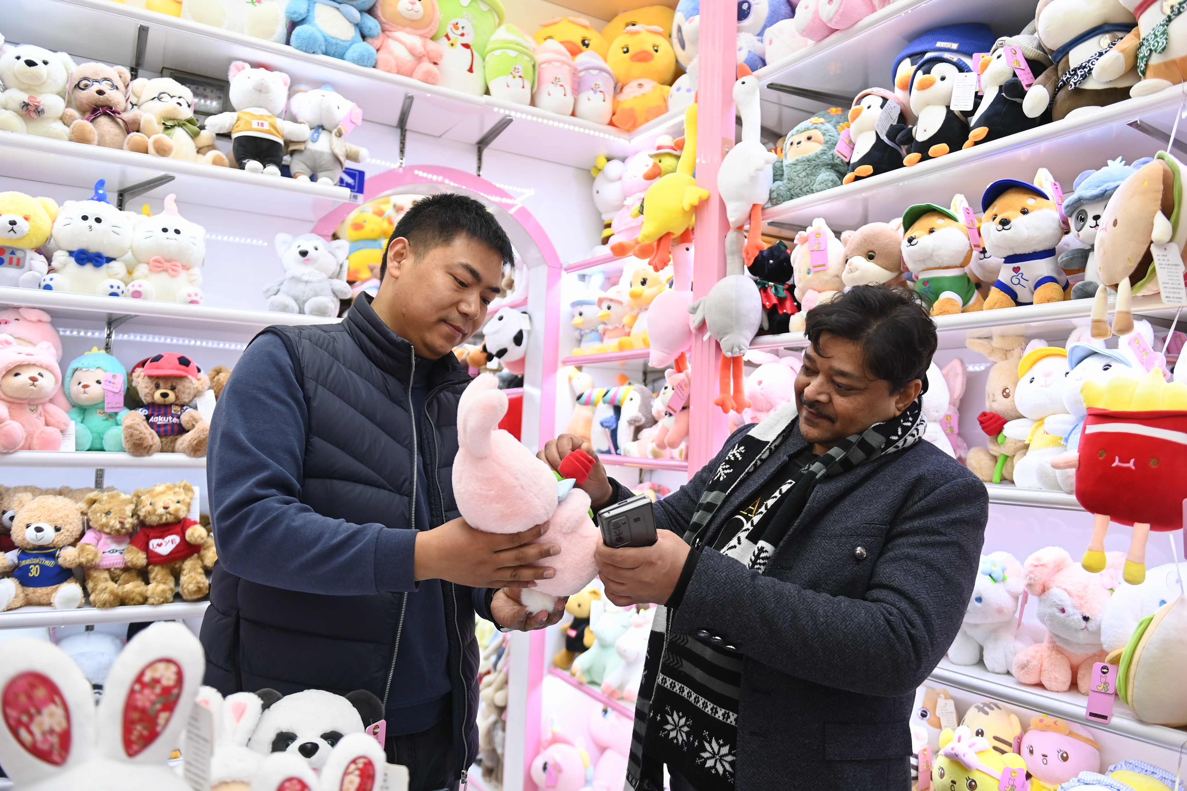 2023年2月2日，來自印度的客商（右）在義烏國際商貿(mào)城的一家玩具店鋪內(nèi)選購。