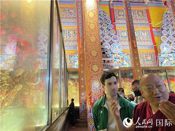 7月25日，省級非物質文化遺產(chǎn)項目塔爾寺酥油花的代表性傳承人朋措堅參（右）在塔爾寺酥油花館講解酥油花的制作過程。人民網(wǎng) 謝瑩攝