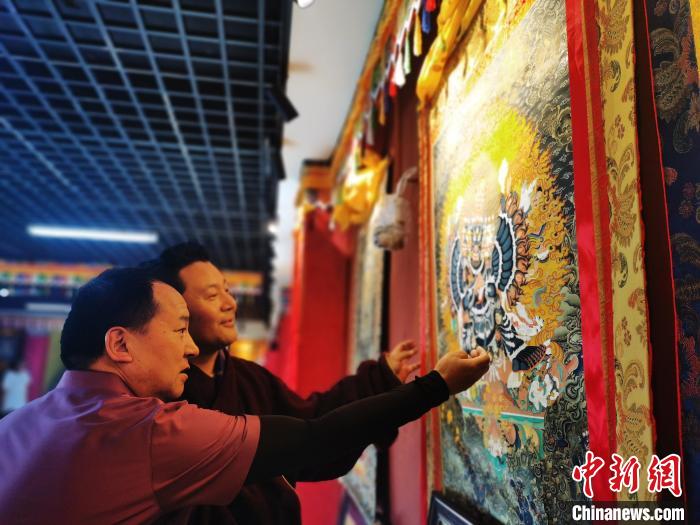 圖為久美尖措展示唐卡作品?！?zhí)砀?攝
