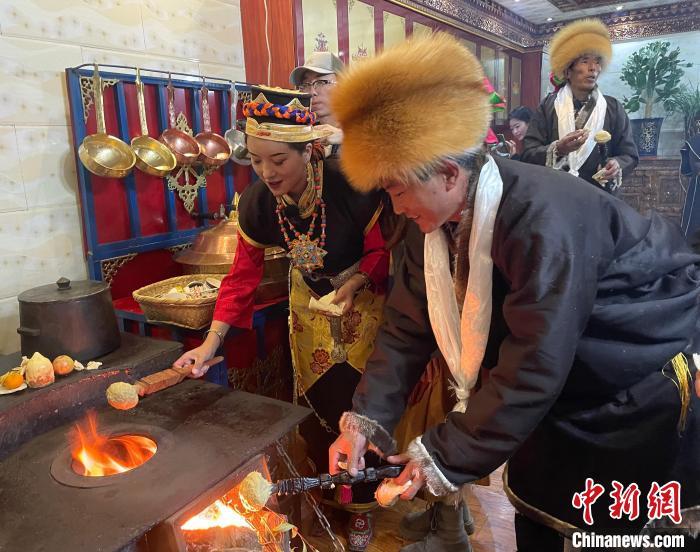 圖為人們在火上烤節(jié)日美食“結(jié)達”?！∪轿木?攝