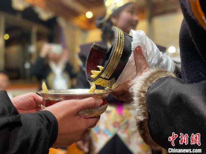 圖為主人在碗中斟滿青稞酒?！∪轿木?攝