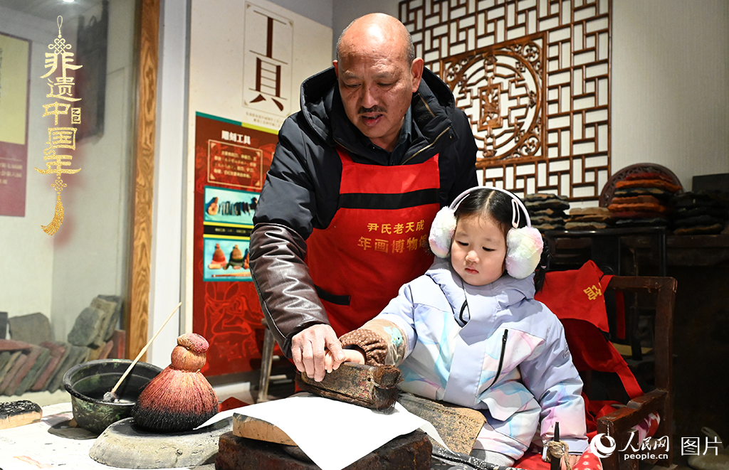 2025年1月27日，河南開封朱仙鎮(zhèn)木版年畫藝人尹國法指導(dǎo)小朋友研習(xí)年畫印制技藝。朱仙鎮(zhèn)木版年畫源自漢唐壁畫藝術(shù)，是中國木版年畫的鼻祖。2006年5月20日，朱仙鎮(zhèn)木版年畫經(jīng)國務(wù)院批準(zhǔn)列入第一批國家級非物質(zhì)文化遺產(chǎn)名錄。人民網(wǎng)記者 王玉興攝